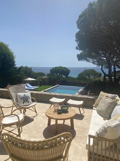 Swimming pool with sunbeds and a terrace with sea and pool view.