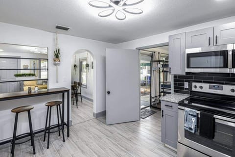 The kitchen is equipped with spacious cabinets, a 4-burner stove with an oven, a microwave, and a large refrigerator. It also features a convenient laundry area with a washer and dryer, as well as a bar with stools