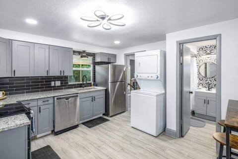 The kitchen is equipped with spacious cabinets, a 4-burner stove with an oven, a microwave, and a large refrigerator. It also features a convenient laundry area with a washer and dryer