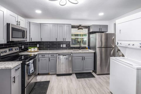 The kitchen is equipped with spacious cabinets, a 4-burner stove with an oven, a microwave, and a large refrigerator. It also features a convenient laundry area with a washer and dryer
