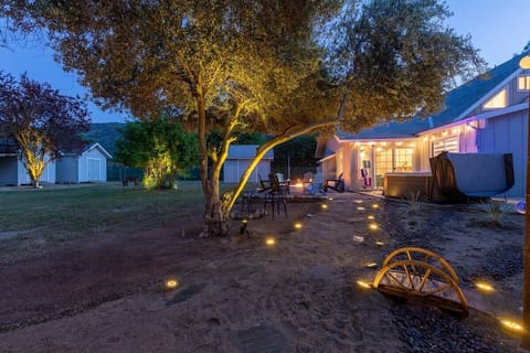 Backyard at night with view of hot tub and firepit.