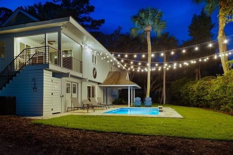 Night-time view of front yard with covered porch with the fabulous pool.
