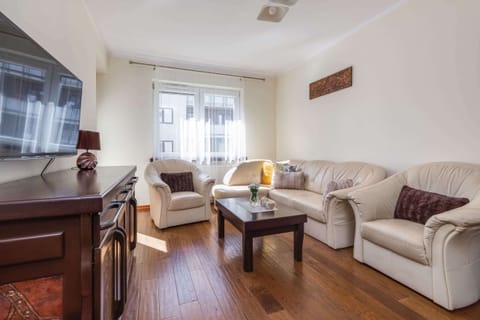 A warm, cozy living room with classic wooden furniture, leather sofas, and a coffee table, all set on wooden flooring.