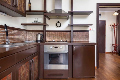 A modern kitchen corner with brick-style tiling and rustic wooden cabinetry, equipped with appliances and stylish décor.