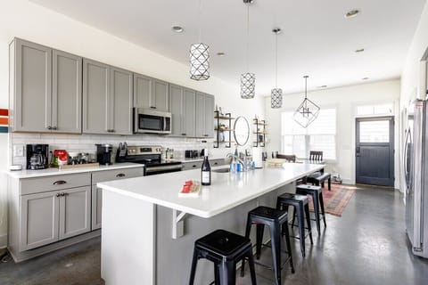 The kitchen features stainless steel appliances and a large island with seating for four at the barstools.