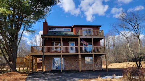 Front deck with seating and balcony with view of lake and pool