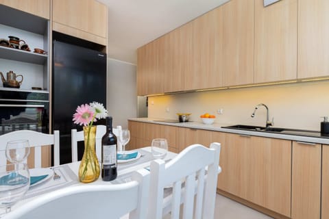 A modern kitchen with wooden cabinetry, ample counter space, and a bright dining area with white furniture.