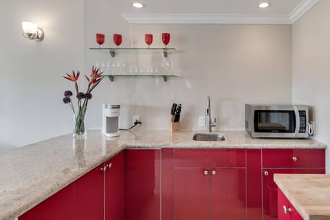 Kitchenette with microwave, mini fridge, Keurig coffee maker, glasses, plates, and cutlery
