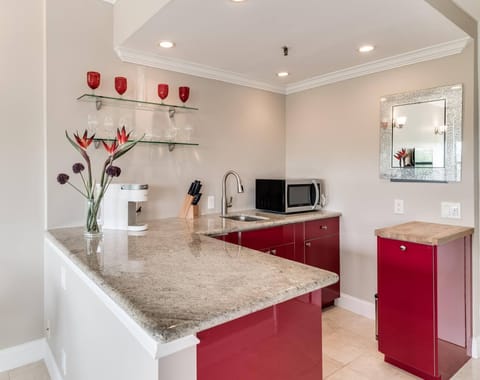 Kitchenette with microwave, mini fridge, Keurig coffee maker, glasses, plates, and cutlery
