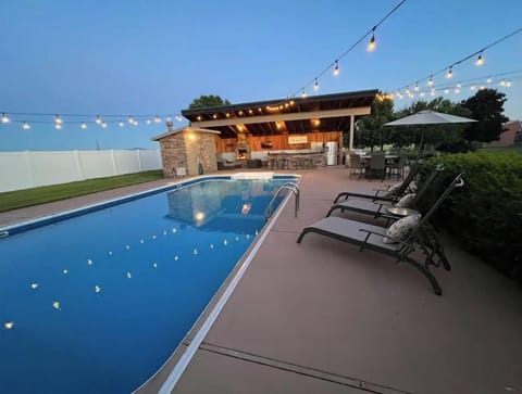 Large heated pool with outdoor lights and lounge chairs. 
