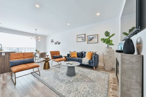 Stylish open-concept living room with designer furniture, a cozy fireplace, and large windows for natural light.