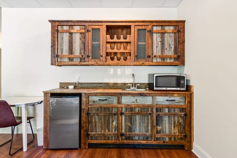 Basement bar with sink microwave, refrigerator and work table.