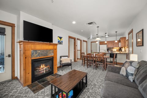 Cozy fireplace lounge with open kitchen, dining space, and mountain-lodge charm