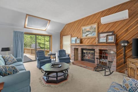 Cozy living room w/ smart tv, fireplace, split AC unit and sliding glass doors lead to wrap around porch.