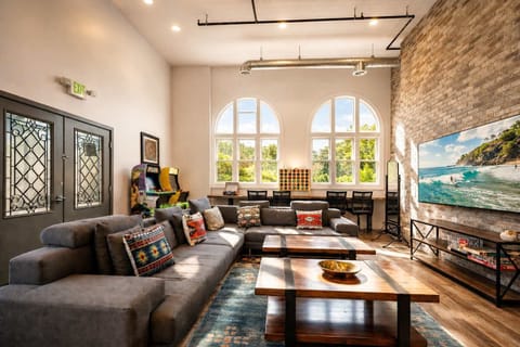 Open-Concept Living Room with High Ceilings, Stone Accent Wall, Large TV, and Ample Seating — Comfortable, Bright, and Ideal for Relaxation