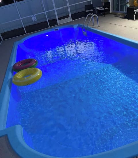 A softly lit nighttime pool reflects shimmering lights on its serene surface.