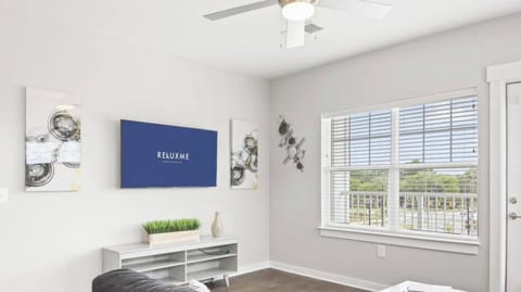 Bright and spacious living room area with large sectional and smart TV..