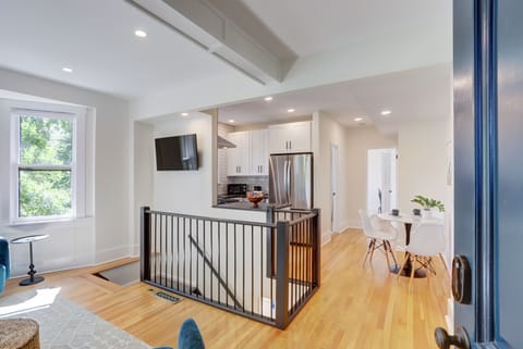 View into kitchen and dining, TV on wall and and stairs to lower level