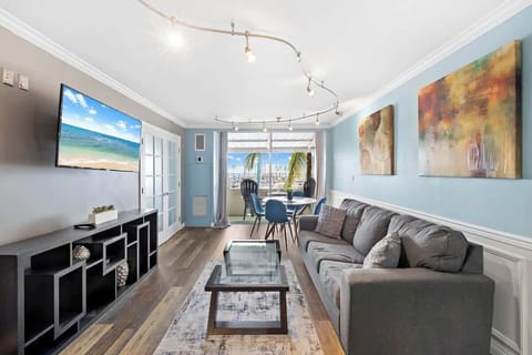 
Modern living room featuring a dining or relaxing area by the balcony, showcasing marina views and abundant natural light, all set on chic wood-like flooring.