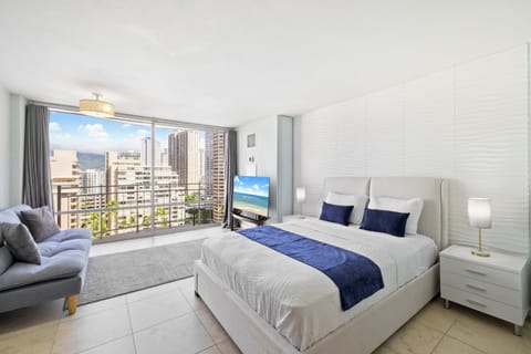 Bright studio with a queen bed, cozy sofa, and private balcony offering city views.