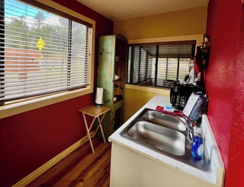 Kitchen nook includes double sink, microwave, coffee maker, and cabinet with dishes, cups/mugs, and cooking/eating utensils