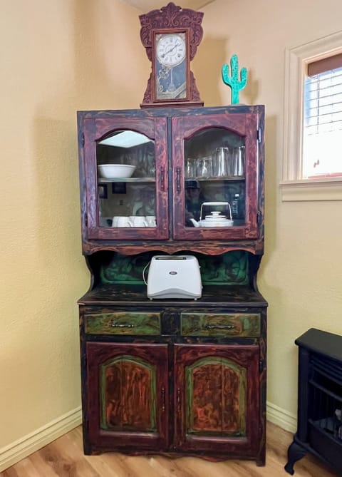 Rustic dining hutch stores dishes, glasses, coffee cups, teapot, and other kitchen/dining amenities.