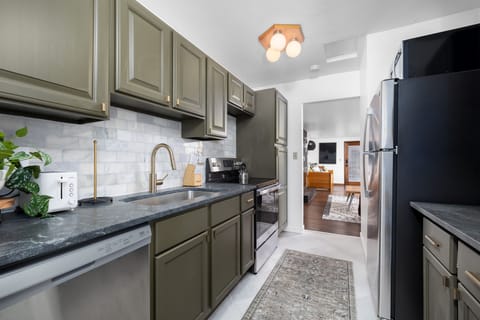 Kitchen with electric stove, full refrigerator, sink and dishwasher. 