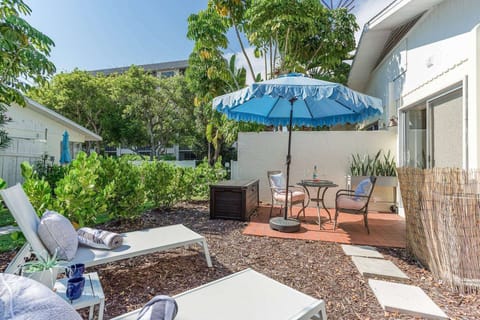 Open outdoor patio with a cafe style table, umbrella and two loungers.  Beach items included.