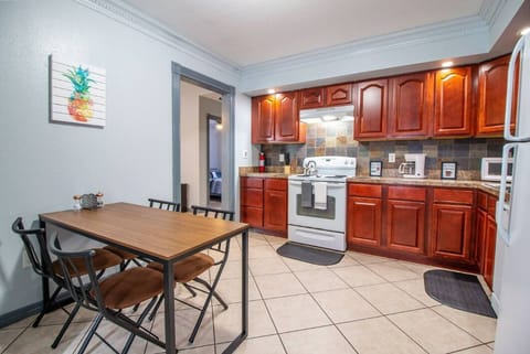 Kitchen with dark wood cabinets and a four-burner stove. Next to it is a wooden dining table with four chairs.