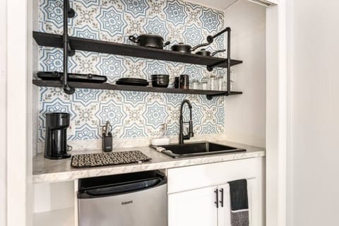 The bar in the room is compact and elegant, featuring a small countertop, sink, and mini-fridge