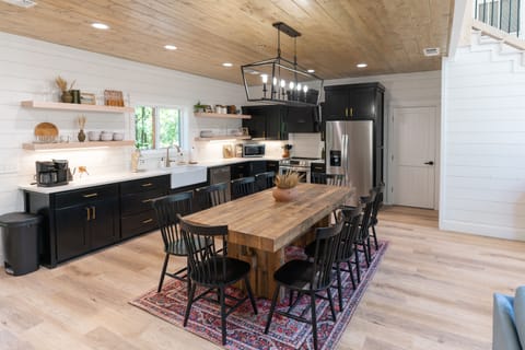 A fully stocked eat in kitchen with modern appliances and a sink that overlooks the trees through the back deck