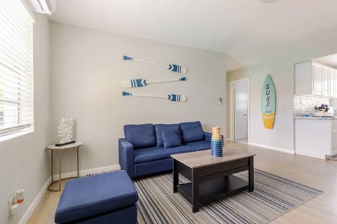 Cozy living room with a blue couch and decorative surfboards on the wall.