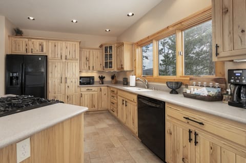 - Spacious kitchen with custom wood cabinetry and scenic window views - Black appliances blend with rustic style for convenience and charm - Fully stocked cooking space perfect for preparing meals together
