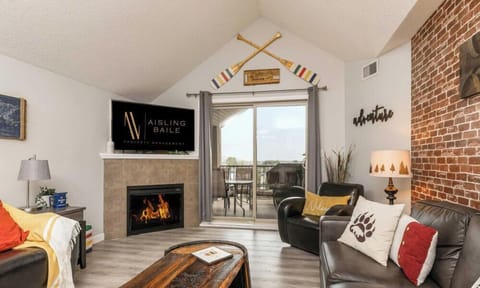 Living room with a smart TV, electric fireplace, cozy seating options and walkout access to the private, top-floor balcony.