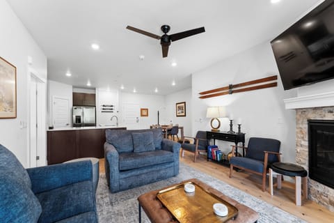 Unwind in your stylish living space with plush blue seating, warm fireplace, and modern kitchen—perfect for cozy evenings.