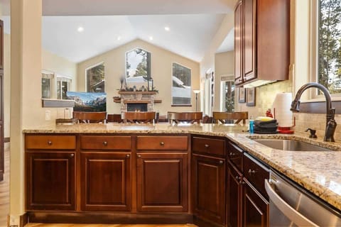 The kitchen boasts ample seating space with a bar featuring four barstools, a large island with two stools, and a dining nook with a table and chairs for six.