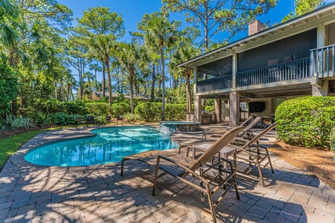 The expansive outdoor haven features a pool, hot tub, multiple seating areas, a smart TV, a well-appointed bar area with a built-in Bull grill, and an outdoor shower.