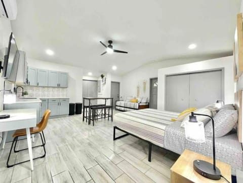 This unit features a comfortable bed, a fully-equipped kitchen, a dining area, a desk for work, a ceiling fan to keep the space cool, and a TV for entertainment. Everything is designed to provide comfort and functionality in one space.