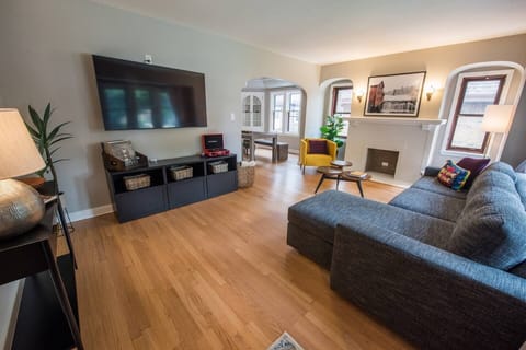 The living room has a sleeper sofa, a 65 inch TV, vinyl records, and toys for the kids