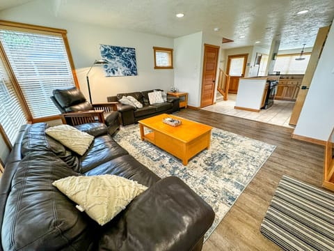Spacious and sunlit living room with plush leather seating, perfect for unwinding after a day of coastal adventures