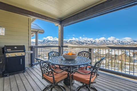 - Covered deck with outdoor dining table and fire feature centerpiece  
- Scenic mountain views surround private balcony with BBQ grill  
- Comfortable seating creates perfect spot for morning coffee or evening meals