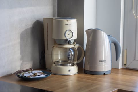 A coffee station setup with a kettle, coffee machine, and mugs, ready for use.
