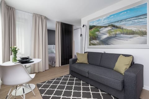 Modern living room with a cozy gray sofa, a coffee table, and large wall art depicting a beach scene.

