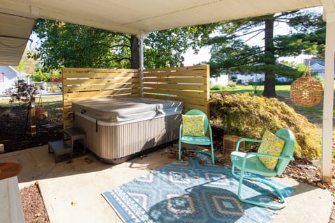 Unwind in your private hot tub on the covered patio, where cheerful seating and garden views create the perfect retreat.