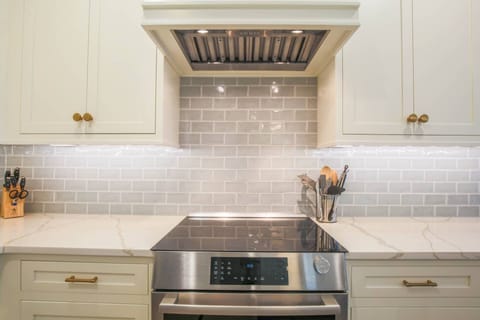 The kitchen features stainless steel appliances, white cabinetry and a tiled backsplash.