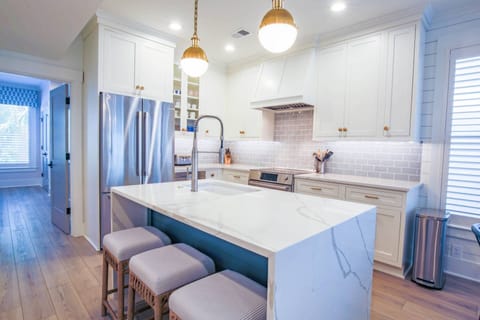 The kitchen centers around the island with waterfall counters, pendant lighting and a sink.