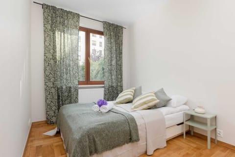 Bright bedroom with green curtains and neatly arranged bedding.
