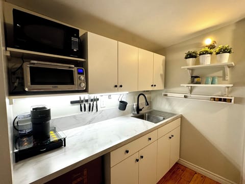 Fridge, cooktop, microwave, toaster, Nespresso, blender, utensils, dining area.