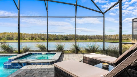 Lakefront poolside retreat with spa, loungers, and peaceful nature views.