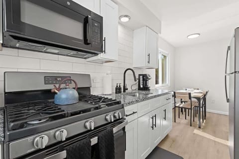 This bright and contemporary galley kitchen features granite countertops, stainless steel appliances, and a cozy dining nook bathed in natural light — perfect for enjoying meals at home.